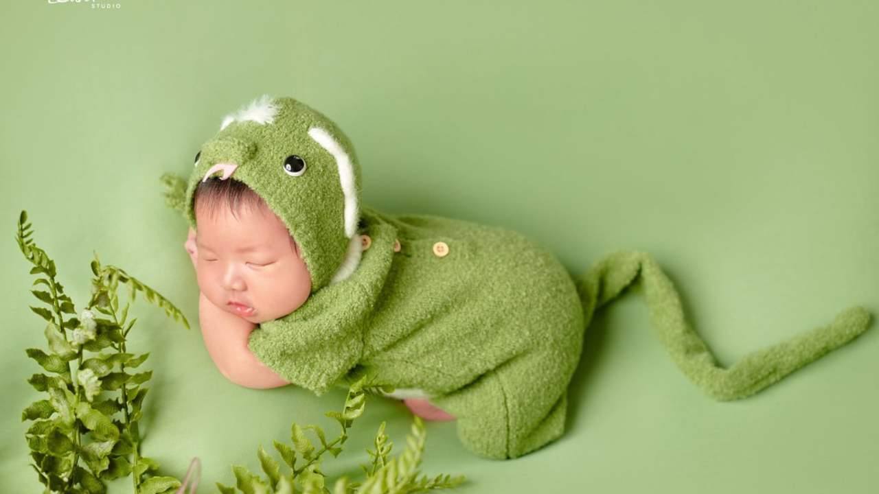 Bé sơ sinh ngủ trong trang phục thú màu xanh